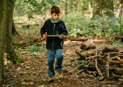 Ein Kind sucht einen größeren Ast aus dem Wald